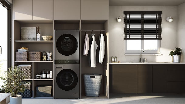 „LG WashTower“ pilkoje skalbykloje, įmontuotos lentynos, matinės spintelės, kriauklės siena ir užtamsintas lango šviestuvas.